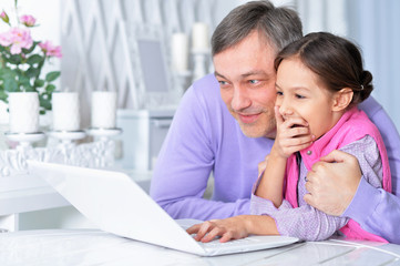 Portrait of father with little daughter using laptop