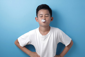 Cute Asian boy eating bubble gum and blow balloon