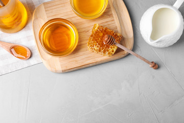 Flat lay composition with tasty honey on light grey table, space for text