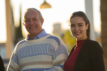 Mature couple gray-haired man and young woman enjoying company outdoor portrait casual meeting. Latin brunette woman and mature Latin man smiling at the camera. Smiling couple.