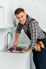 happy installer holding plunger near sink in kitchen