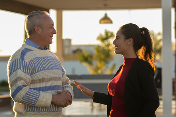 Mature couple gray-haired man and young woman enjoying company outdoor portrait casual meeting. Latin brunette woman and mature Latin man smiling at the camera. couple talking.