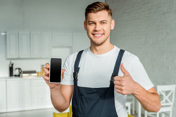 happy installer holding smartphone with blank screen and showing thumb up