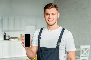 happy installer holding smartphone with blank screen and looking at camera