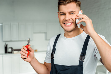happy installer talking on smartphone and holding pliers