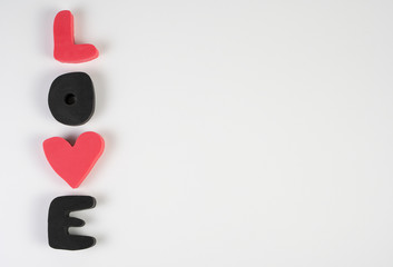 The inscription "Love" of plastic letters in pink and black on a white background, the concept for Valentine's Day, wedding, birthday and other holidays, the view from the top.