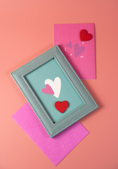 Blue frame with hearts and pink envelopes on a pink background, concept for Valentine's Day, wedding, birthday and other holidays, view from the top.
