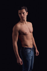 Fototapeta na wymiar barechested guy with a dramatic light in the Studio. looking to the side pathetic