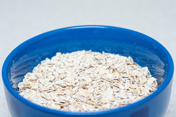 Oatmeal in a blue plate on a white kitchen table. Side view of an athlete's perfect breakfast.