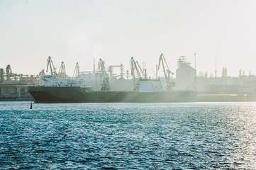 A large empty ship is parked at the top of an industrial base in the sea. The rays of the sun break through the dust.