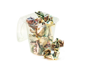 Crumpled dollar bills in the trash bin isolated on white background. Crumpled money in the transparent trash basket