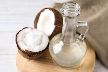 Fototapeta na wymiar Coconut oil in glass jug on white table, closeup