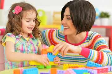 Fototapeta premium Portrait of young mother playing with little daughter