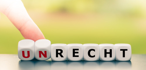 Hand dreht Würfel und ändert das Wort Unrecht in Recht.