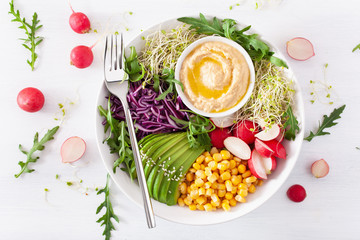 vegan avocado sweet corn lunch bowl with hummus, red cabbage, radish and sprouts