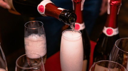 Close-up of champagne pouring into a wine glass. Concept of restaurant and catering service