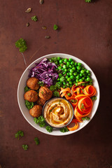 healthy vegan lunch bowl with falafel hummus carrot ribbons cabbage and peas