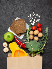 Paper bag vegetables and fruit on a dark background. Copy space, top view.