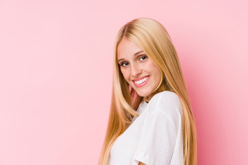 Young blonde woman face closeup isolated on a pink background
