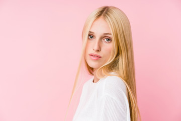 Young blonde woman face closeup isolated on a pink background
