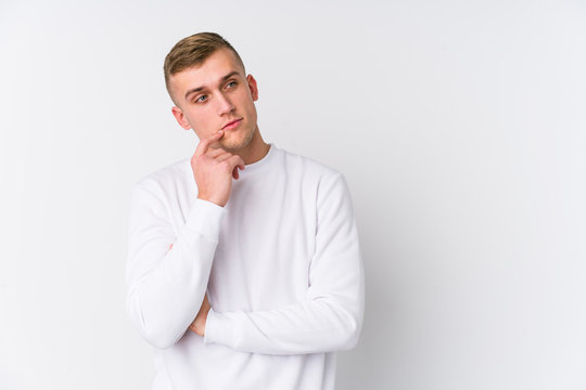 Young caucasian man on white background relaxed thinking about something looking at a copy space.