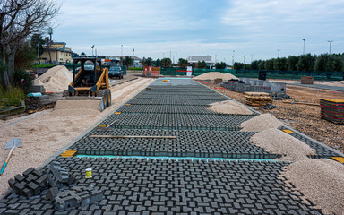 Paving stone worker is putting down pavers during a construction of a city street.