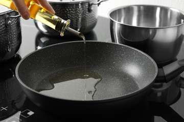 Woman pouring cooking oil from bottle into frying pan, closeup