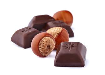 Closeup shot of cut dark chocolate with hazelnuts on white background.