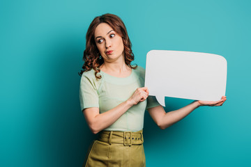 skeptical girl grimacing while holding speech bubble on blue background