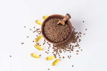 A gelatin capsules with linseed oil and a cup wiyh flax seeds on a light background with copy space.
