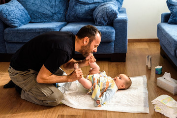 Father changing his daughter's dirty diaper on the living room floor.