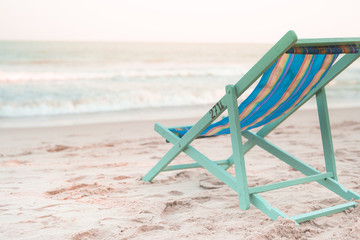 Fototapeta na wymiar beach chair at side of beach with sunset background on autumn season