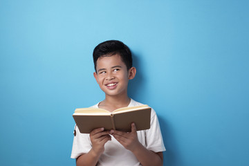 Obraz premium Asian boy looking up thinking expression while reading a book