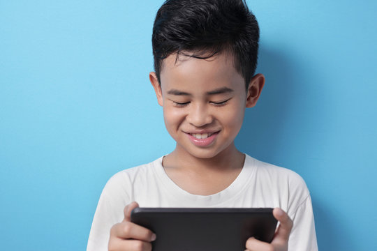 Asian Boy Plays Online Game On His Tablet Gadget