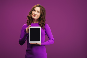 smiling woman holding digital tablet with blank screen on purple background