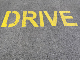 Drive written in yellow on asphalt road