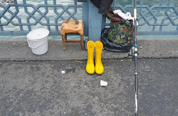 Yellow rubber boots and fishing rod on bridge side
