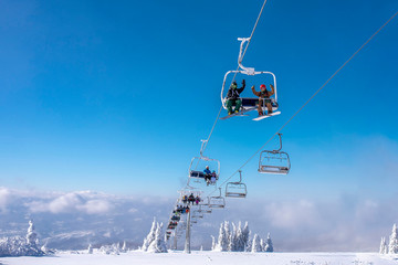People enjoying winter sports. Skiers on chairlift at mountain ski resort 