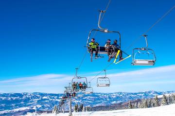 Family winter vacation concept. Skiers on chairlift at mountain ski resort 