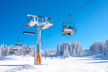 Winter sports concept. Skiers on chairlift at mountain ski resort  - obrazy, fototapety, plakaty