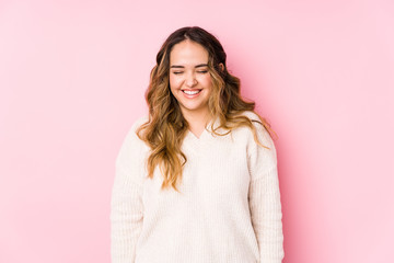 Young curvy woman posing in a pink background isolated laughs and closes eyes, feels relaxed and...