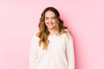 Obraz premium Young curvy woman posing in a pink background isolated laughs and closes eyes, feels relaxed and happy.