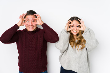 Young couple posing in a white background keeping eyes opened to find a success opportunity.