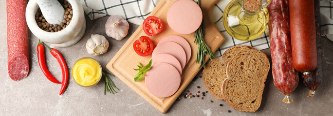 Sausages, bread, spices, towel and board on grey background, space for text