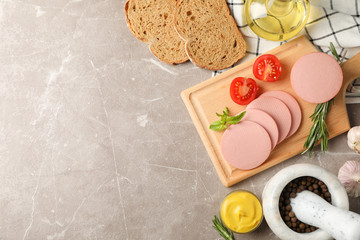 Sausage, bread, spices, towel and board on grey background, space for text
