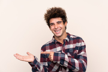 Young caucasian man holding copyspace imaginary on the palm to insert an ad