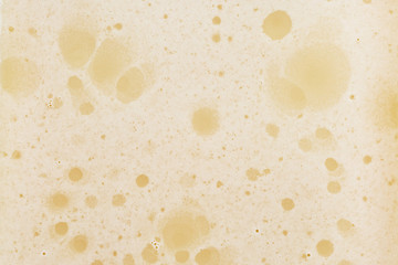 Unfiltered beer with foam background, texture, close up