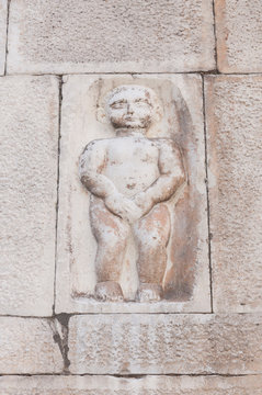 Carrara, Italy: bas-relief depicting a puppet covering his private parts on the facade of a building in Duomo square