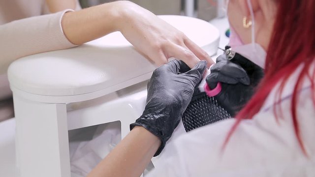 Woman manicurist with gloves in a beauty salon does a hardware manicure to a client before applying a gel coating. translation from blur to sharpen