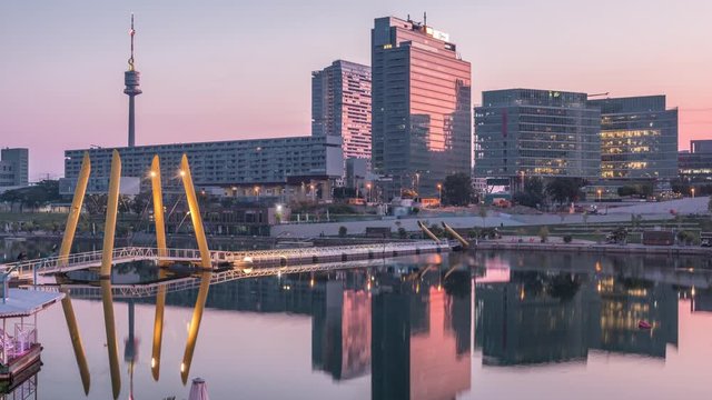 Donaustadt Danube City night to day transition timelapse is a modern quarter with skyscrapers and business centres in Vienna, Austria. Modern architecture and pedestrian bridge illuminated at morning